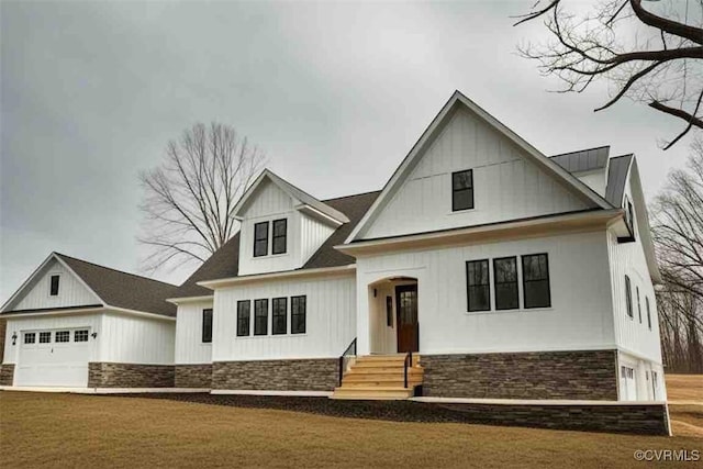 modern farmhouse with stone siding, board and batten siding, and a front lawn