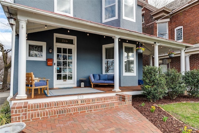 doorway to property with a porch and stucco siding