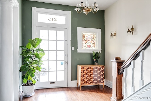 doorway featuring a chandelier, stairs, baseboards, and wood finished floors