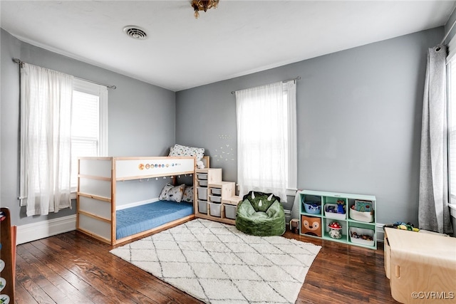 bedroom with visible vents, multiple windows, baseboards, and hardwood / wood-style floors