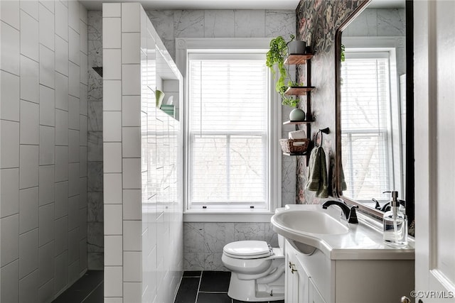 bathroom featuring vanity, tile walls, toilet, and tile patterned floors