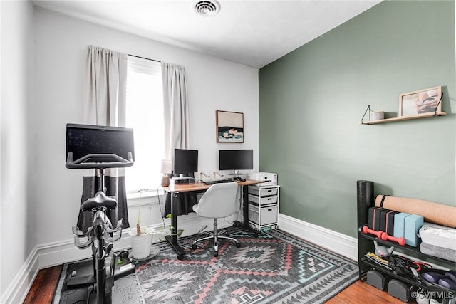 office with wood finished floors, a healthy amount of sunlight, visible vents, and baseboards