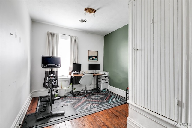 office space featuring wood finished floors, visible vents, and baseboards