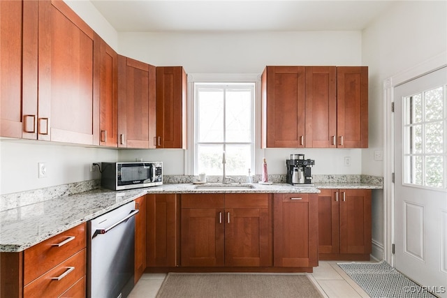 kitchen with light stone counters, brown cabinets, appliances with stainless steel finishes, and a sink