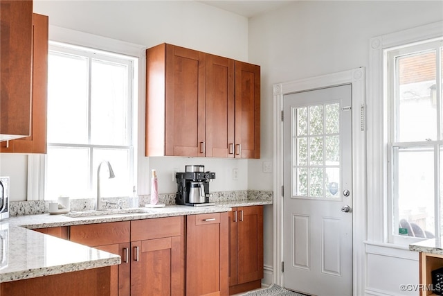 kitchen with light stone counters, brown cabinets, and a sink