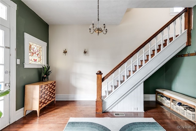 entrance foyer featuring visible vents, wood finished floors, baseboards, a chandelier, and stairs