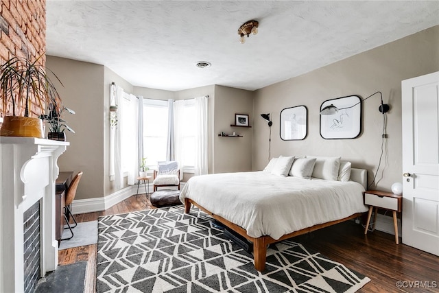 bedroom featuring visible vents, a textured ceiling, baseboards, and wood finished floors