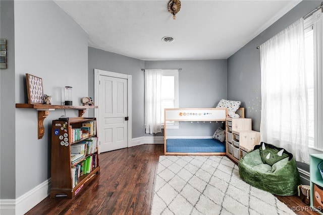 bedroom with visible vents, baseboards, and wood finished floors