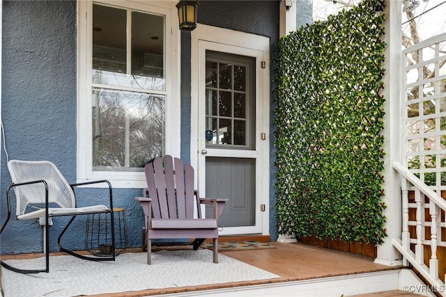 property entrance featuring a porch and stucco siding