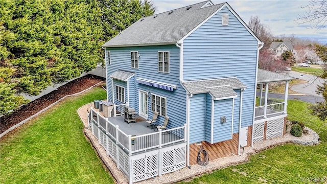 rear view of property featuring a sunroom, a shingled roof, central air condition unit, a lawn, and brick siding