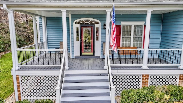 doorway to property with a porch and a shingled roof