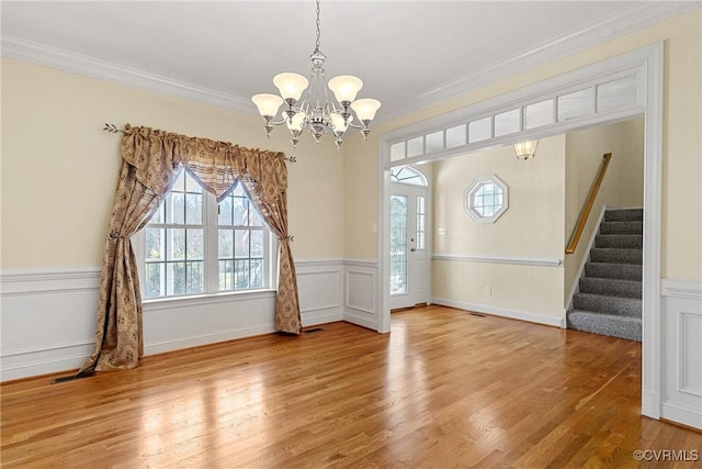 interior space featuring a notable chandelier, wood finished floors, stairs, and crown molding