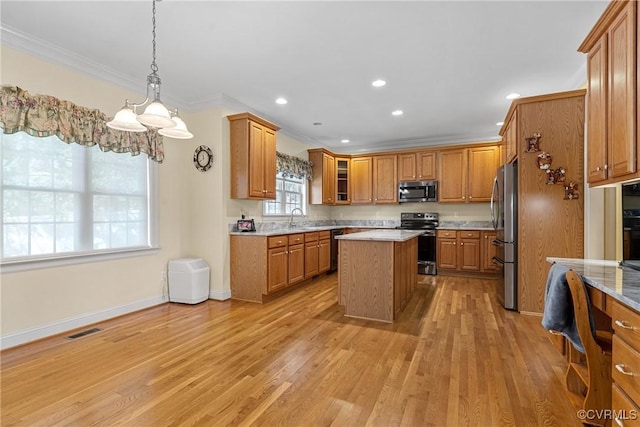 kitchen featuring light wood-style flooring, a sink, a center island, stainless steel appliances, and crown molding