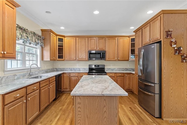 kitchen featuring a kitchen island, ornamental molding, light wood-style flooring, appliances with stainless steel finishes, and a sink