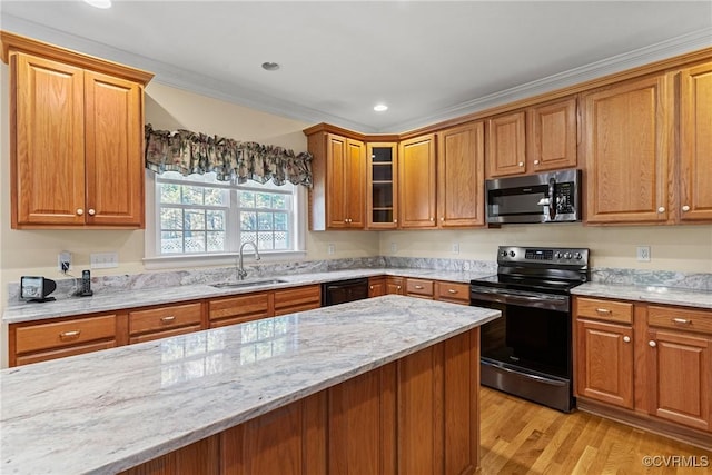 kitchen featuring black appliances, light wood-style flooring, a sink, light stone counters, and brown cabinetry