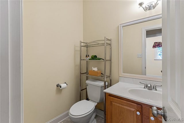 bathroom with baseboards, toilet, and vanity