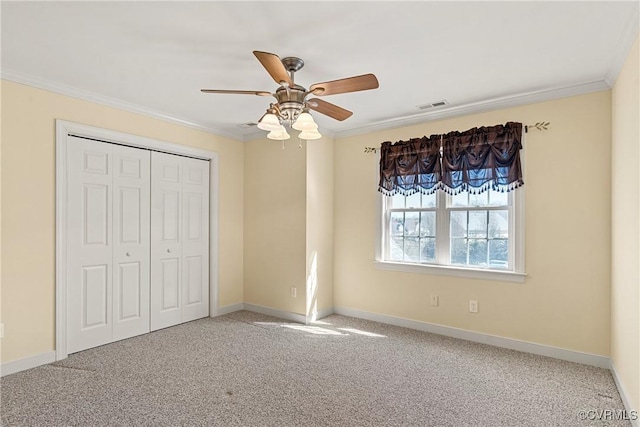 unfurnished bedroom with visible vents, baseboards, ornamental molding, carpet flooring, and a closet