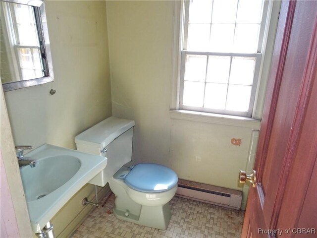 bathroom featuring a baseboard heating unit, a sink, toilet, and tile patterned floors