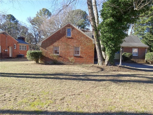 view of front of property with central air condition unit, a front lawn, and brick siding