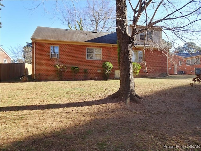 rear view of house featuring a yard, crawl space, brick siding, and fence