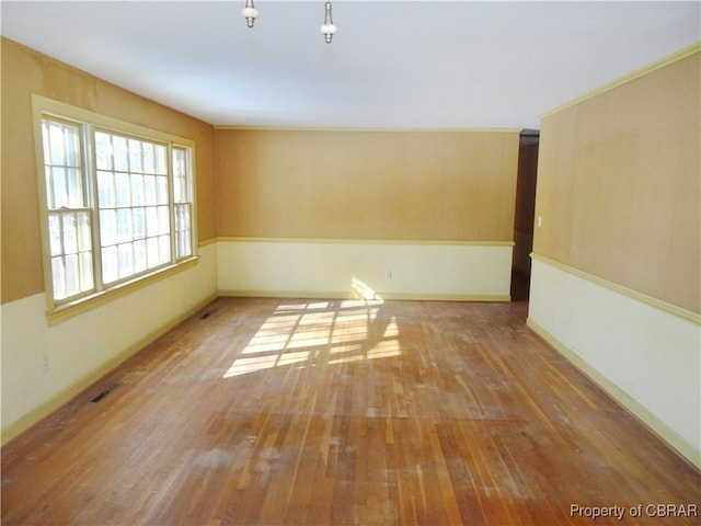 spare room featuring visible vents, hardwood / wood-style flooring, and baseboards