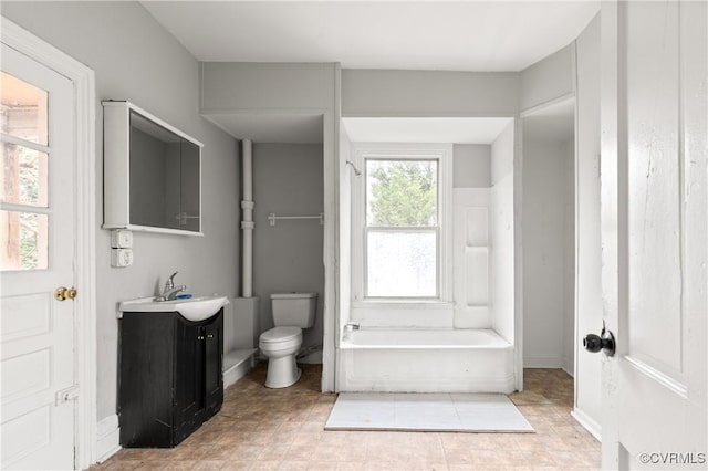 bathroom with toilet, a tub to relax in, baseboards, and vanity