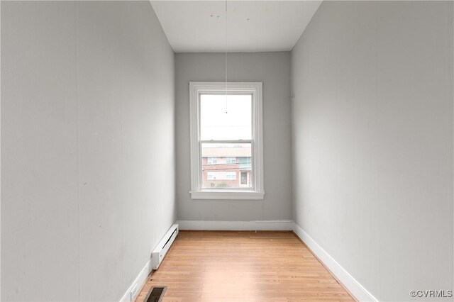 unfurnished room with attic access, baseboards, visible vents, baseboard heating, and light wood-style floors