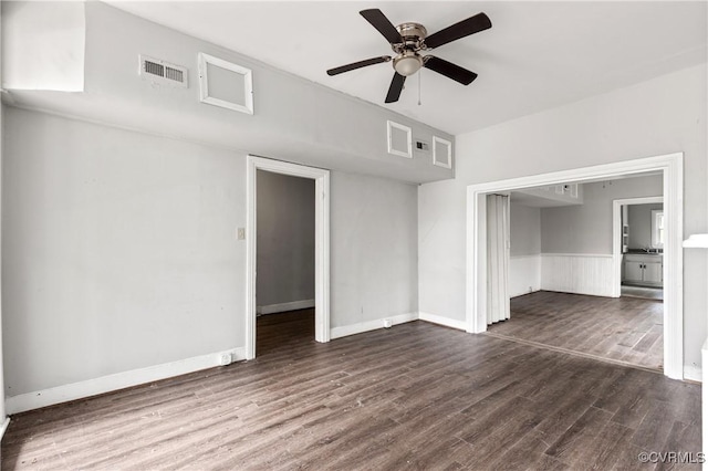 spare room featuring baseboards, dark wood-style flooring, visible vents, and a ceiling fan