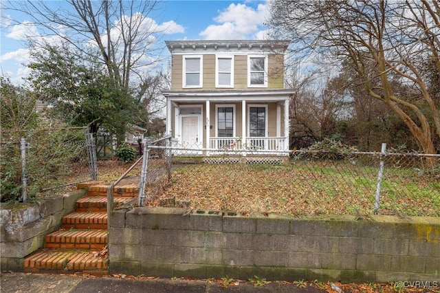 italianate-style house featuring covered porch and a fenced front yard