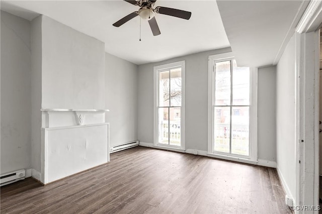 spare room featuring a ceiling fan, baseboards, a baseboard heating unit, and wood finished floors