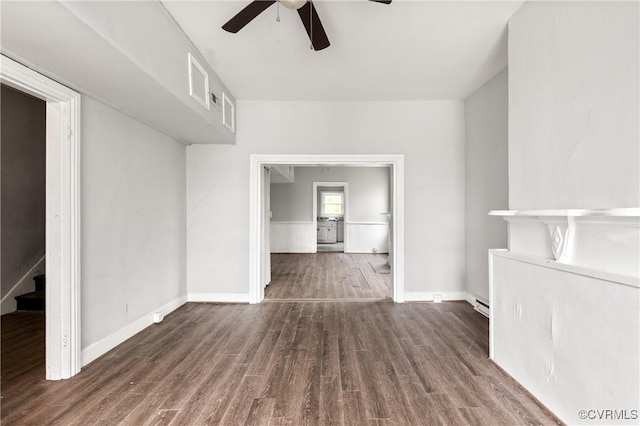 interior space featuring ceiling fan, a baseboard radiator, wood finished floors, baseboards, and stairway