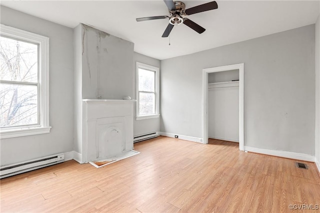 unfurnished bedroom with light wood finished floors, baseboard heating, visible vents, and baseboards