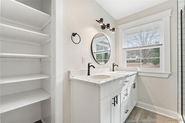 full bathroom with a sink, baseboards, and double vanity