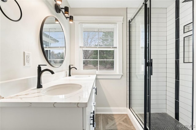 bathroom with a stall shower, a sink, and baseboards