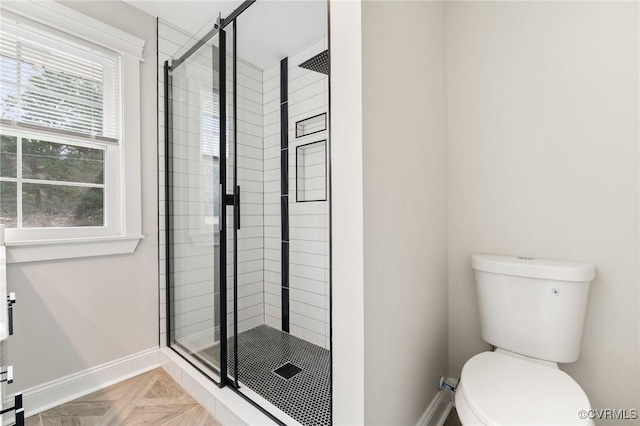 bathroom with a stall shower, a wealth of natural light, toilet, and baseboards