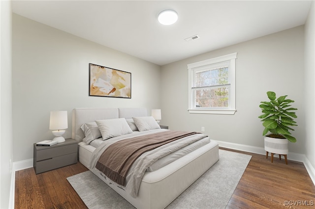 bedroom with dark wood-style floors, visible vents, and baseboards