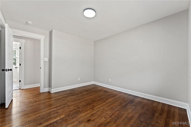 spare room featuring dark wood finished floors and baseboards