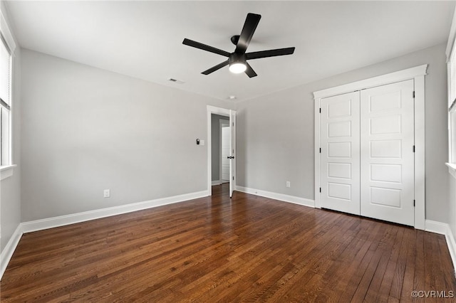 unfurnished bedroom featuring dark wood-type flooring, a closet, visible vents, and baseboards