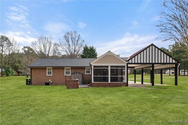 rear view of house featuring a sunroom, a patio area, a yard, and brick siding