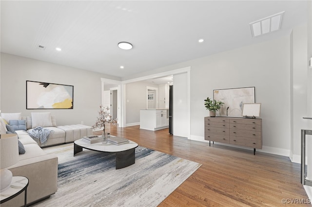 living area featuring light wood-type flooring, visible vents, baseboards, and recessed lighting