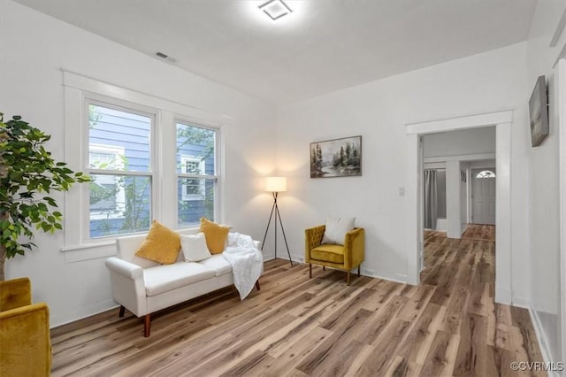 sitting room featuring visible vents, light wood-style flooring, and baseboards