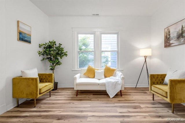 sitting room featuring light wood-type flooring, visible vents, and baseboards