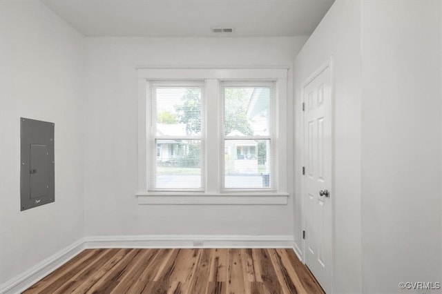 unfurnished room featuring baseboards, electric panel, visible vents, and wood finished floors