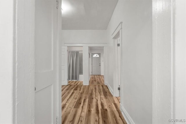 hall featuring light wood finished floors and baseboards