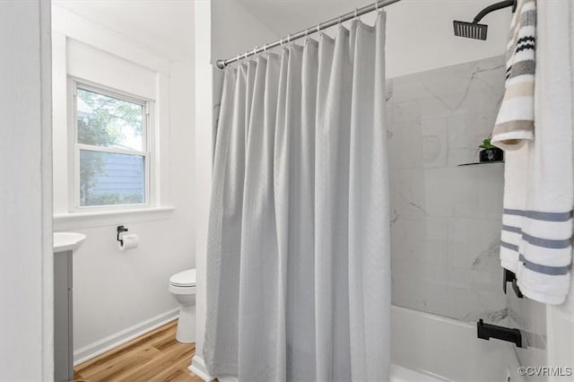 bathroom featuring toilet, shower / bath combo, vanity, wood finished floors, and baseboards