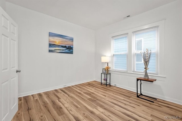 unfurnished room with light wood-type flooring, visible vents, and baseboards