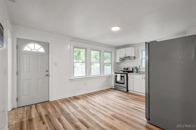 kitchen with appliances with stainless steel finishes, white cabinetry, light wood-style floors, and under cabinet range hood