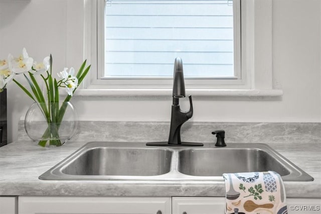 interior details with light countertops, white cabinetry, and a sink