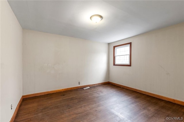 empty room featuring visible vents, baseboards, and wood finished floors