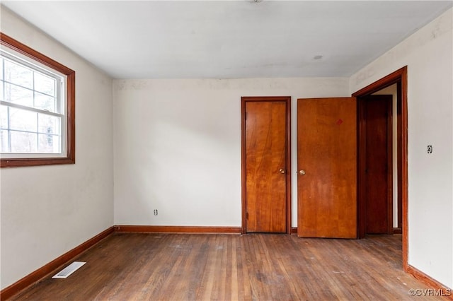 unfurnished bedroom featuring wood-type flooring, visible vents, and baseboards